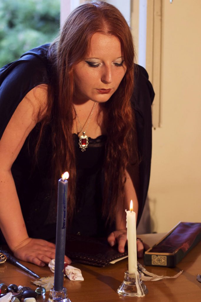 La professoressa Mayfire nella sua aula, con candele, talismani e bacchette magiche